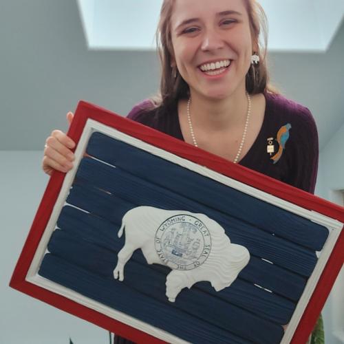 Kylie McCormick holding a wooden replica of the Wyoming State flag