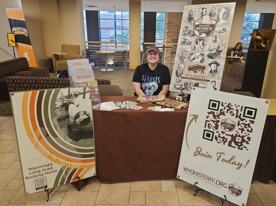 Person sits at a table surrounded by posters with information about the Wyoming Historical Society