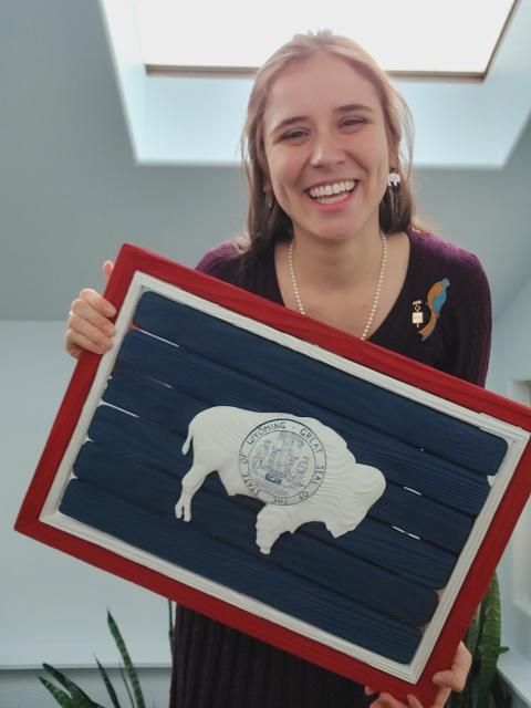 Kylie McCormick holding a wooden replica of the Wyoming State flag