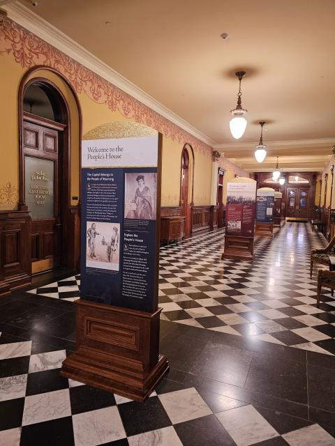 Long hallways with multiple interpretive signs along a checkerboard floor